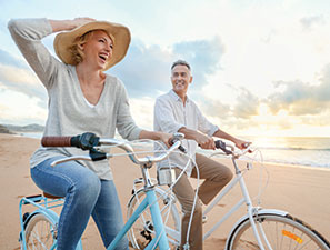 Couple riding bikes on the beach. Link to Gifts of Life Insurance